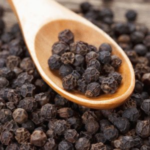 Grains de poivre noir bio sur une cuillère en bois
