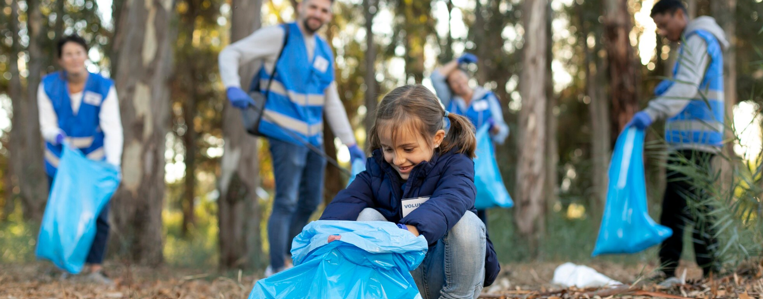 Enfant et adultes ramassant des déchets en forêt avec des sacs bleus